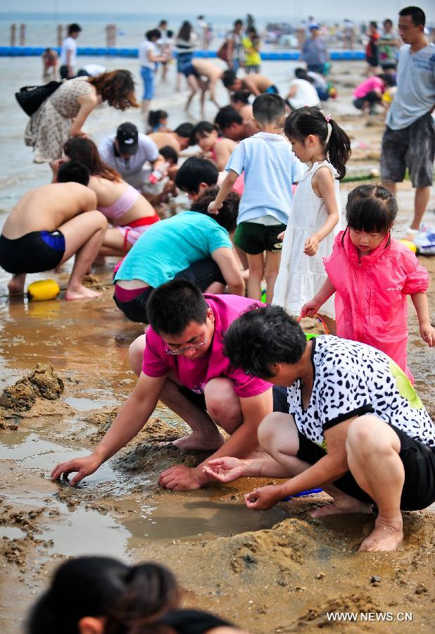 People search for shells on the bathing beach in Dongjiangwan of north China's Tianjin Municipality, June 30, 2013. Many people came to Dongjiangwan to spend their weekends. (Xinhua/Zhang Chaoqun)