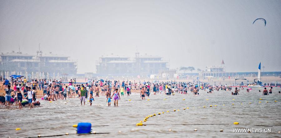 People swarm to the bathing beach in Dongjiangwan of north China's Tianjin Municipality, June 30, 2013. Many people came to Dongjiangwan to spend their weekends. (Xinhua/Zhang Chaoqun)