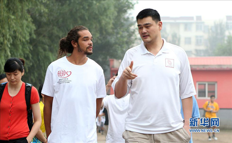 Former NBA star Yao Ming (R) talks with Joakim Noah of Chicago Bulls during their visit to a primary school for children from migrant workers' families in Changping district in the northern suburbs of Beijing, Sunday, June 30, 2013. The visit is part of the Yao Foundation charity events in 2013, which inlcude a charity basketball game on July 1, 2013 in MasterCard Center in Beijing. 