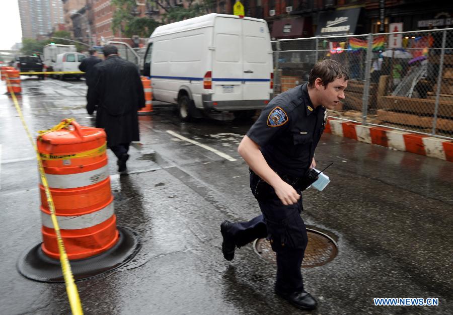 A police officer investigates at the crime scene in New York, the United States, on July 1, 2013. The male victim, a 56-year-old construction worker, was shot in the chest on West 49th Street and Ninth Avenue around 9 a.m. The victim was taken to Roosevelt Hospital. The suspect, believed to be an ex-employee of the same construction compnay, fled the scene in a white vehicle. He is considered armed and dangerous, according to the police. (Xinhua/Wang Lei)