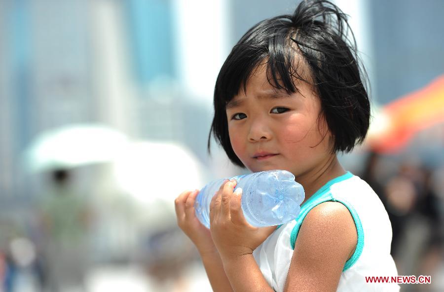 A girl cools herself off with a bottle of chilled water at the Nanjing Road in Shanghai, east China, July 2, 2013. Shanghai meteorological bureau issued an orange-coded heat alert Tuesday, as parts of the city have been under the highest temperature of 38 degrees Celsius. (Xinhua/Lai Xinlin) 