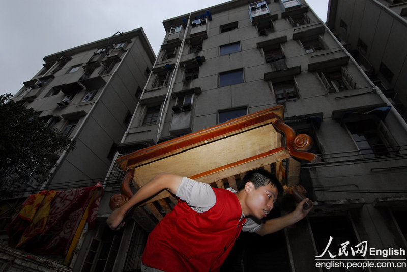 Yuan Zhengxun carries furniture in a residential community of Changsha on Aug. 30, 2009. Yuan worked for a movement company. He earned 1,500 yuan per month, and lived with other workers in a humble room.  (Photo/CFP)