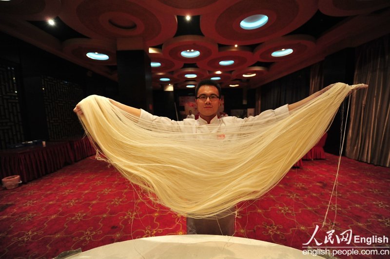 Fan Bo shows the skill of noodles making in Taiyuan on April 18, 2011. His specialty in college was dancing.  (Photo/CFP)