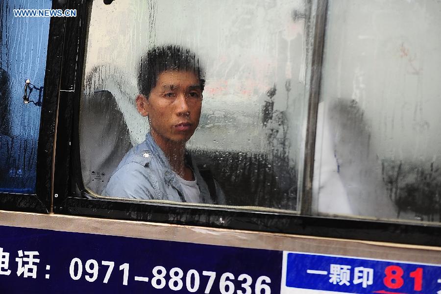 A passenger looks out of the window in a bus in Xining, capital of northwest China's Qinghai Province, July 3, 2013. Xining was hit by rainfall in most parts of the city on Wednesday, which brought cool weather. (Xinhua/Li Shaopeng) 