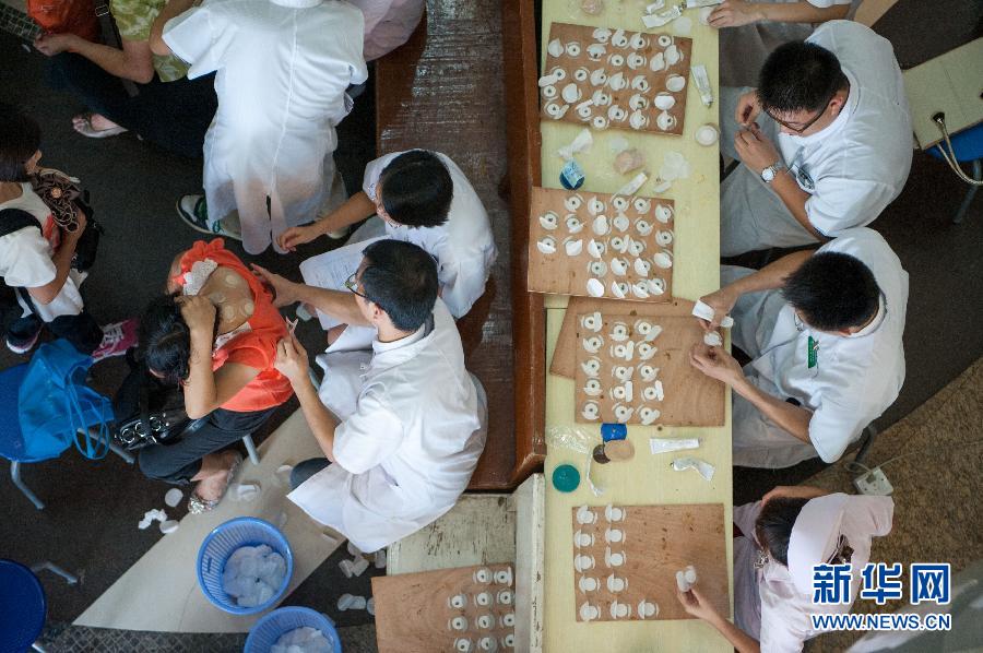 Doctors apply "hot summer days plaster medicine" to local residents at the Guangdong Provincial Traditional Chinese medical hospital July 3, 2013. (Photo: Mao Siqian/Xinhua)