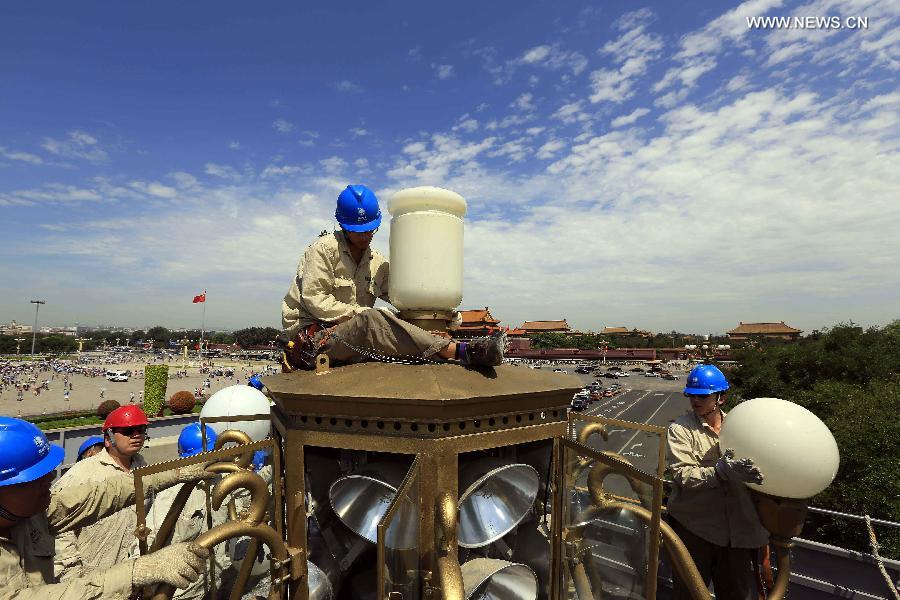 Workers clean and overhaul a lamp during the annual maintenance of city lamps near Tian'anmen Square, Beijing, capital of China, July 4, 2013. (Xinhua/Liu Qinzhuang) 