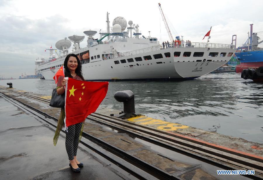 A woman holding a flag of China welcomes Yuanwang V space tracking ship, which is at Tanjung Priok port for a 7-day visit in Jakarta, Indonesia, July 5, 2013. Yuanwang V is a space tracking ship mainly used to manipulate and coordinate the space position of satellites and spaceships. (Xinhua/Zulkarnain) 