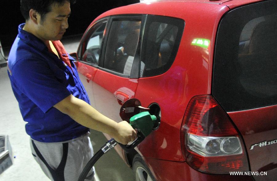 An employee fills the tank of a car at a gas station in Baoding, north China's Hebei Province, July 6, 2013. China cut the retail price of gasoline by 80 yuan (12.9 U.S. dollars) per tonne from Saturday and that of diesel by 75 yuan per tonne, the country's top economic planner said on Friday. (Xinhua/Zhu Xudong)