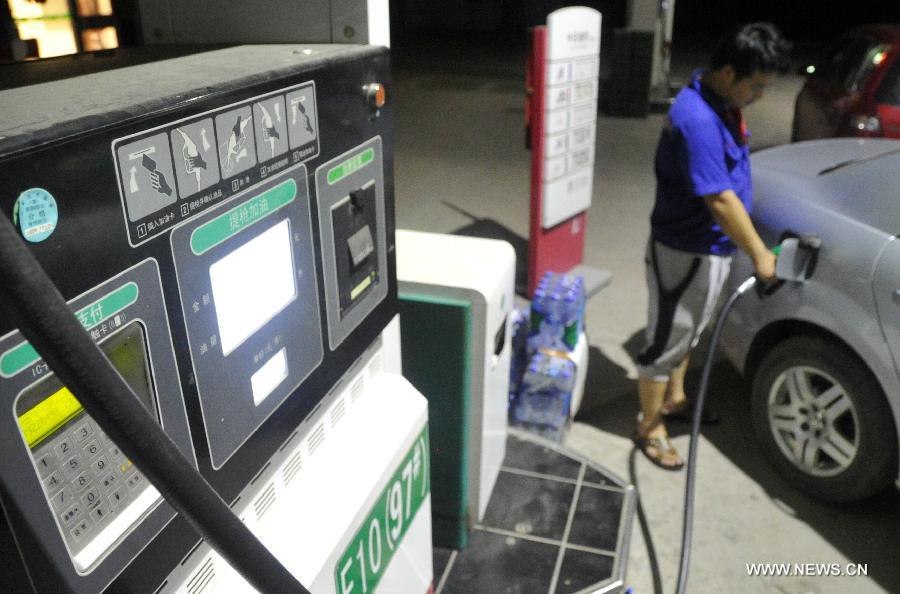 An employee fills the tank of a car at a gas station in Baoding, north China's Hebei Province, July 6, 2013. China cut the retail price of gasoline by 80 yuan (12.9 U.S. dollars) per tonne from Saturday and that of diesel by 75 yuan per tonne, the country's top economic planner said on Friday. (Xinhua/Zhu Xudong)