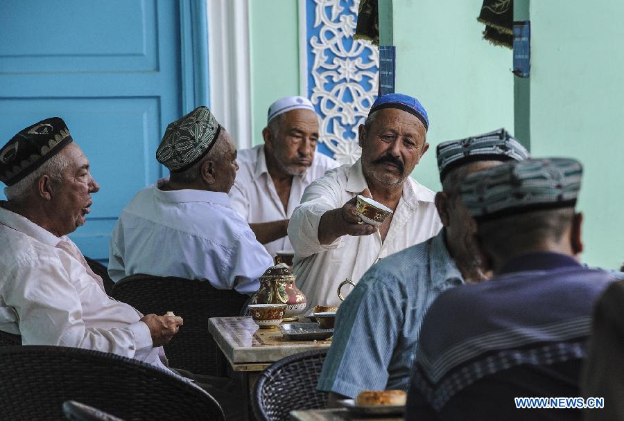 People drink tea at an old teahouse near the Id Kah Square in Kashgar, northwest China's Xinjiang Uygur Autonomous Region, July 5, 2013. With simple decoration, the teahouse is located at the second floor of an old-fishioned building and is favored by the old of Uygur ethnic group. They usually enjoy drinking tea and chatting after every morning prayer. (Xinhua/Shen Qiao)