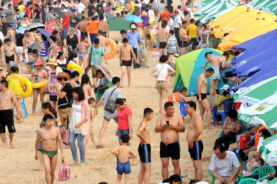 Tourists enjoy coolness at the Dashawan bathing beach in Lianyungang, east China's Jiangsu Province, July 6, 2013. The beach entered its tourism peak season with the rising temperature. (Xinhua/Wang Chun)