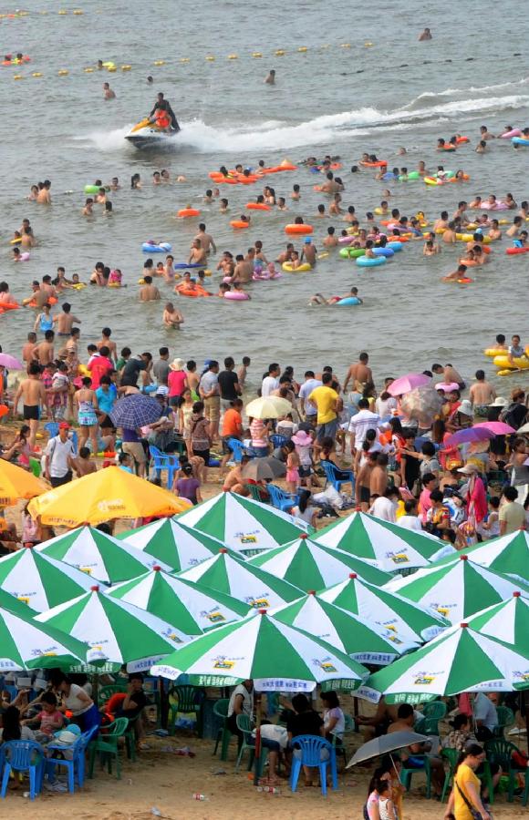 Tourists enjoy coolness at the Dashawan beach in Lianyungang, east China's Jiangsu Province, July 6, 2013. The beach entered its tourism peak season with the rising temperature. (Xinhua/Wang Chun) 