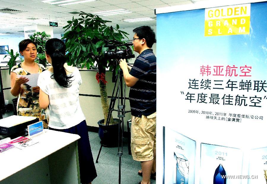 An employee is interviewed by reporters at the office of the Asiana Airlines to Shanghai, east China, July 7, 2013. A total of 141 Chinese citizens were among the 291 passengers aboard the Asiana Airlines flight that crash-landed at the San Francisco International Airport on Saturday, and 90 of the Chinese passengers in total departed from Shanghai via Seoul to the San Francisco airport in the U.S. All the two killed in the crash were identified to be Chinese women, South Korea's transportation ministry said Sunday. (Xinhua/Chen Fei)  