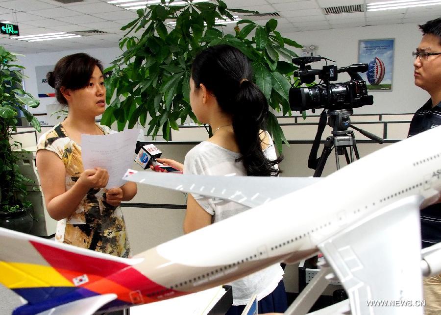 An employee is interviewed by reporters at the office of the Asiana Airlines to Shanghai, east China, July 7, 2013. A total of 141 Chinese citizens were among the 291 passengers aboard the Asiana Airlines flight that crash-landed at the San Francisco International Airport on Saturday, and 90 of the Chinese passengers in total departed from Shanghai via Seoul to the San Francisco airport in the U.S. All the two killed in the crash were identified to be Chinese women, South Korea's transportation ministry said Sunday. (Xinhua/Chen Fei)  