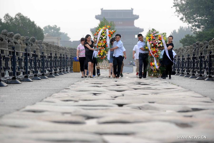 People present flower baskets on the Lugou Bridge during a memorial event marking the 76th anniversary of "The July 7th Incident" in Beijing, capital of China, July 7, 2013. The "July 7 Incident" or the "Lugou Bridge Incident", marked the beginning of the War of Resistance by the Chinese people against Japanese aggression in 1937. (Xinhua/Gong Lei) 