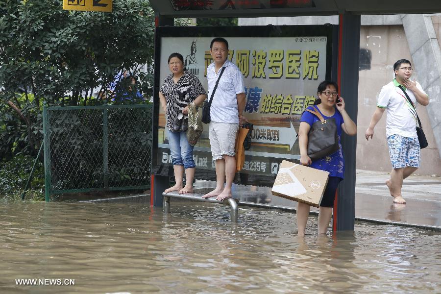 People wait for buses on a flooded road in Wuhan, capital of central China's Hubei Province, July 7, 2013. Wuhan was hit by the heaviest rainstorm in five years from Saturday to Sunday. The local meteorologic center has issued red alerts for rainstorm for many times in sequence. (Xinhua)