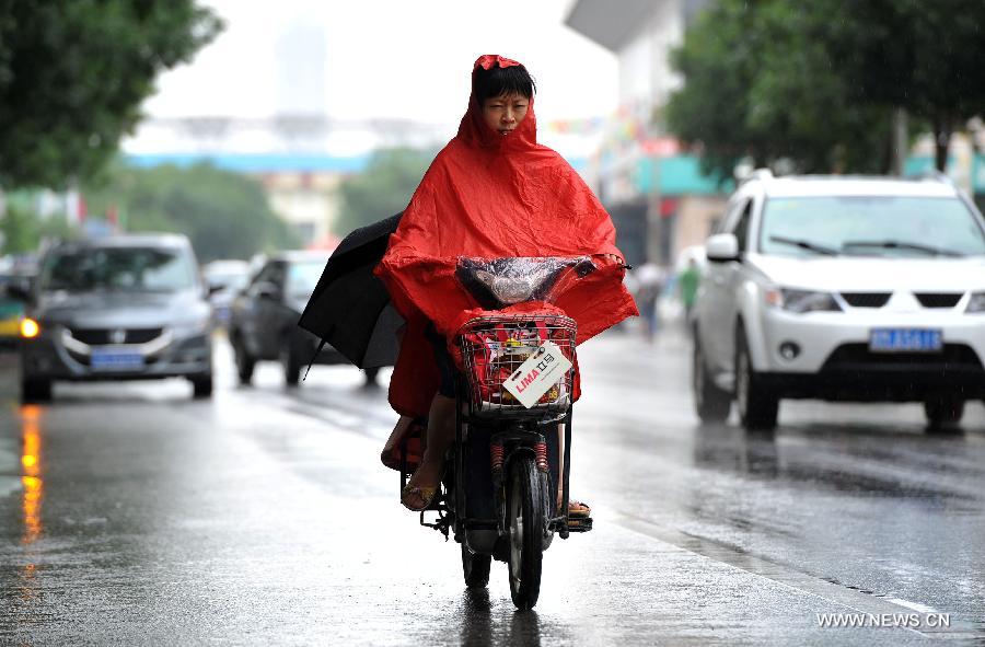 A woman rides with a rain cape in Yinchuan, capital of northwest China's Ningxia Hui Autonomous Region, July 7, 2013. Xiaoshu (Lesser Heat), the 11th of the 24 solar terms in the Chinese Lunar Calendar which means the beginning of hot summer, fell on Saturday. Rainfall brought cool to Yinchuan on Xiaoshu. (Xinhua/Peng Zhaozhi)