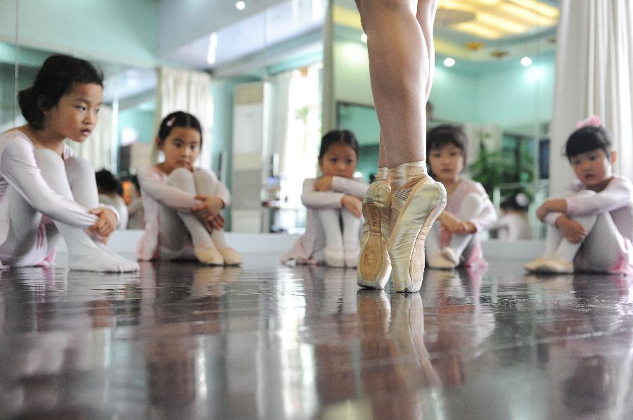 Young girls watch the demonstration of their teacher at a ballet training class during the summer vacation in Shanghai, east China, July 7, 2013. (Xinhua/Lai Xinlin)
