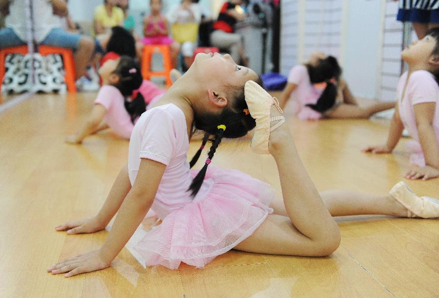 Young girls do physical training at a dance class during the summer vacation in Shanghai, east China, July 7, 2013. (Xinhua/Lai Xinlin)