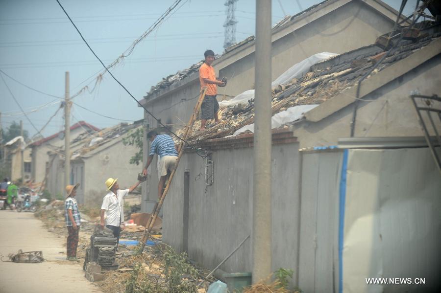 Villagers mend a house roof damged by a tornado in Yuhu Village, Gaoyou City, east China's Jiangsu Province, July 8, 2013. Tornados battered Gaoyou and Yizheng in the province on July 7, making houses and power devices damaged. (Xinhua/Meng Delong)