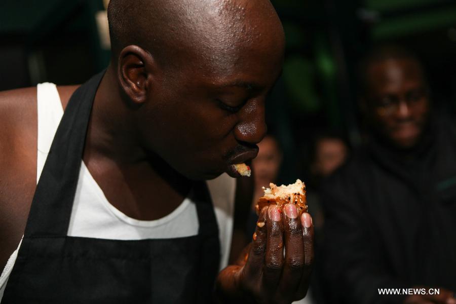A contestant takes part in a burger challenge at Brew Bistro in Nairobi, capital of Kenya, July 9, 2013. Four contestants had one hour to finish a 5kg burger with beef, two huge burger buns and 40 toppings. Sauti Sol team won the burger challenge. (Xinhua/Meng Chenguang)