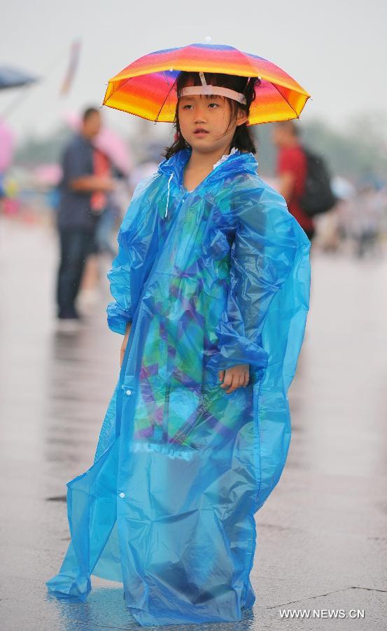 A girl wearing a raincoat and an umbrella-shaped hat visits the Tiananmen Square in Beijing, capital of China, July 9, 2013. Many tourists continue to come to enjoy the scenery of the capital city while Beijing witnessed frequent rainfall recently. The local meteorological observatory observatory issued a warning on torrential rains from Tuesday to Wednesday in Beijing. (Xinhua/Chen Yehua)
