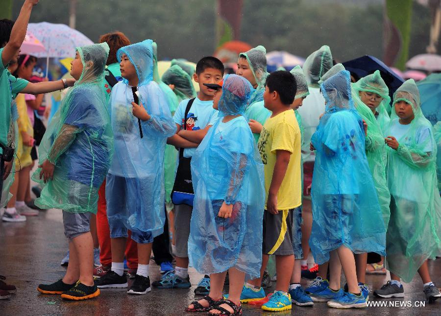 Children wearing raincoats visit the Tiananmen Square in Beijing, capital of China, July 9, 2013. Many tourists continue to come to enjoy the scenery of the capital city while Beijing witnessed frequent rainfall recently. The local meteorological observatory observatory issued a warning on torrential rains from Tuesday to Wednesday in Beijing. (Xinhua/Chen Yehua)