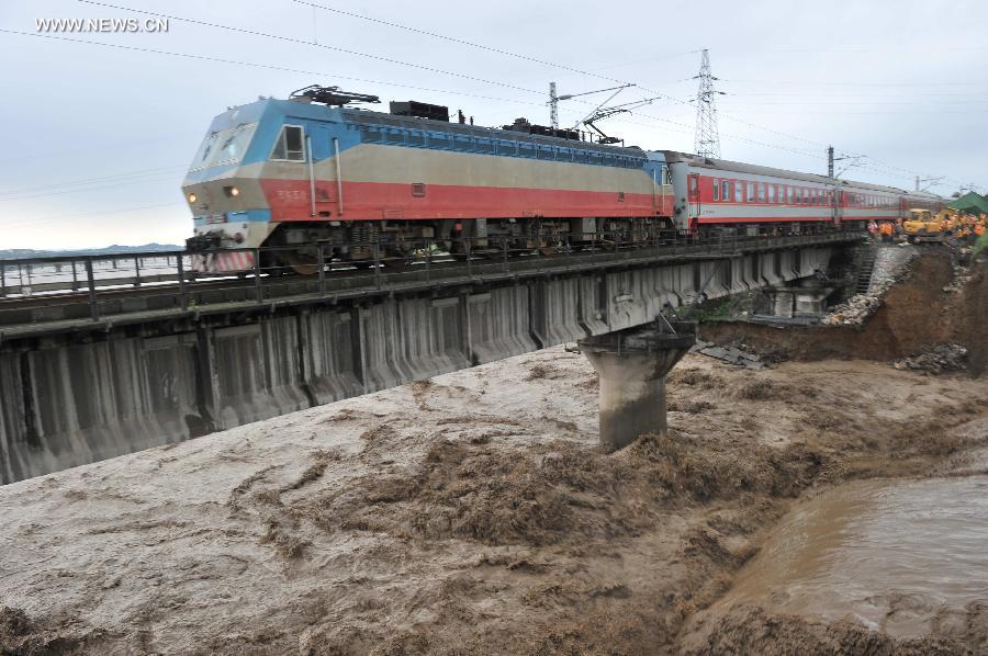 A train runs across the Mianyuan River Bridge of the Baoji-Chengdu Railway in southwest China's Sichuan Province, July 10, 2013. Rainstorm-triggered flood flew through the bridge. (Xinhua/Wang Zhengwei) 