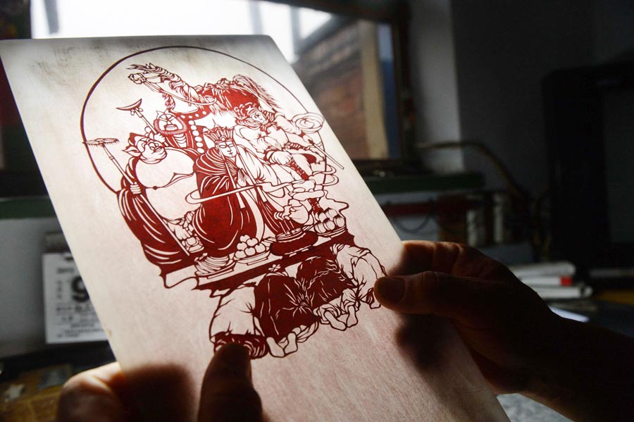 Li Xiangkui, 65, edits his paper-cut work of characters from "Journey to the West" in Cangzhou, Hebei province, July 7, 2013. (Photo/Xinhua)