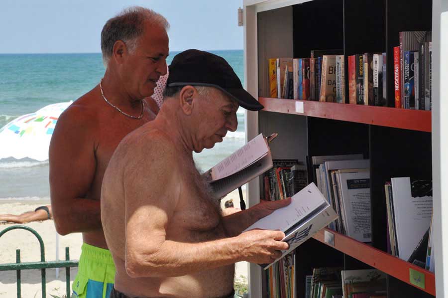 People read books from a beach library in Tel Aviv-Yafo on Tuesday, July 9, 2013. [Photo: CRIENGLISH.com / Zhang Jin]   