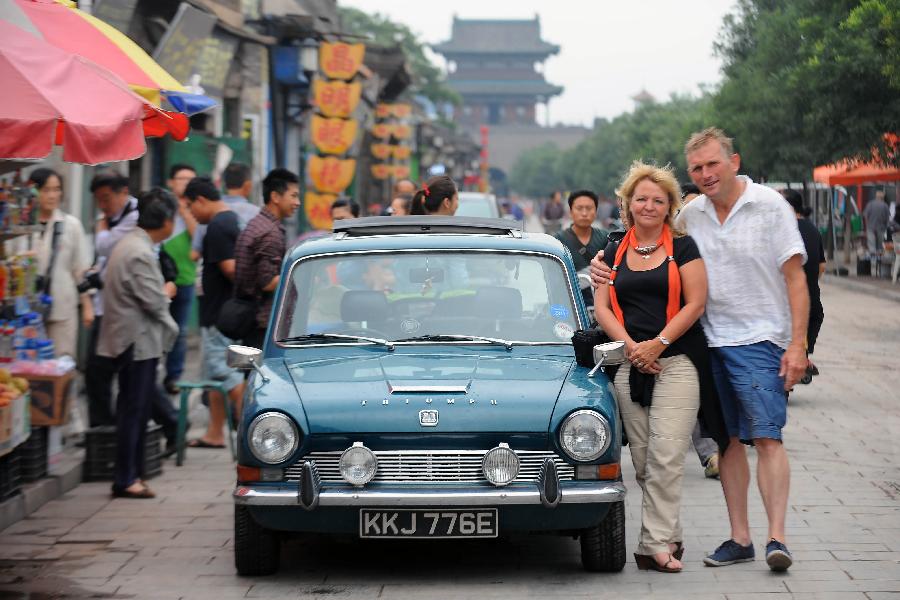 British Clive Raven poses for a photo with his wife Gillian next to their Triumph 1300 which was made in 1967, in Pingyao, north China's Shanxi Province, July 10, 2013. [Photo: Xinhua]