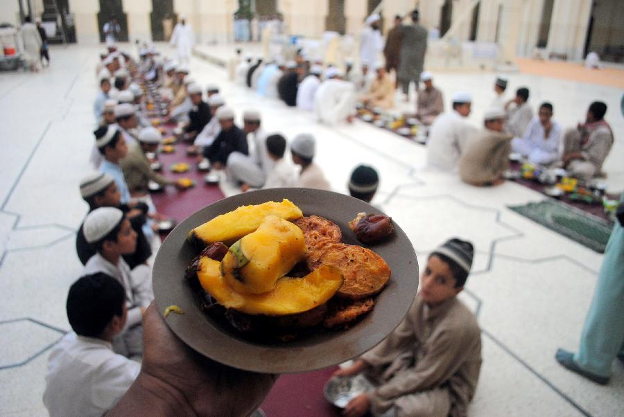 A Pakistani volunteer distributes Iftar for Muslim devotees at a mosque during the first day of the Muslim fasting month of Ramadan in northwest Pakistan's Peshawar on July 11, 2013. Iftar refers to the evening meal when Muslims break their fast during the holly month of Ramadan, a season of fasting and spiritual reflection. (Xinhua/Umar Qayyum) 