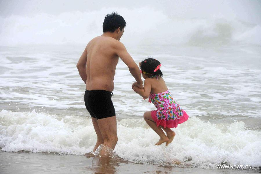 People play on the Jinshatan bathing beach in Qingdao, east China's Shandong Province, July 13, 2013. Saturday marks the beginning of the hottest part of summer. Many people came to the seashore to spend a cool weekend. (Xinhua/Yu Fangping)