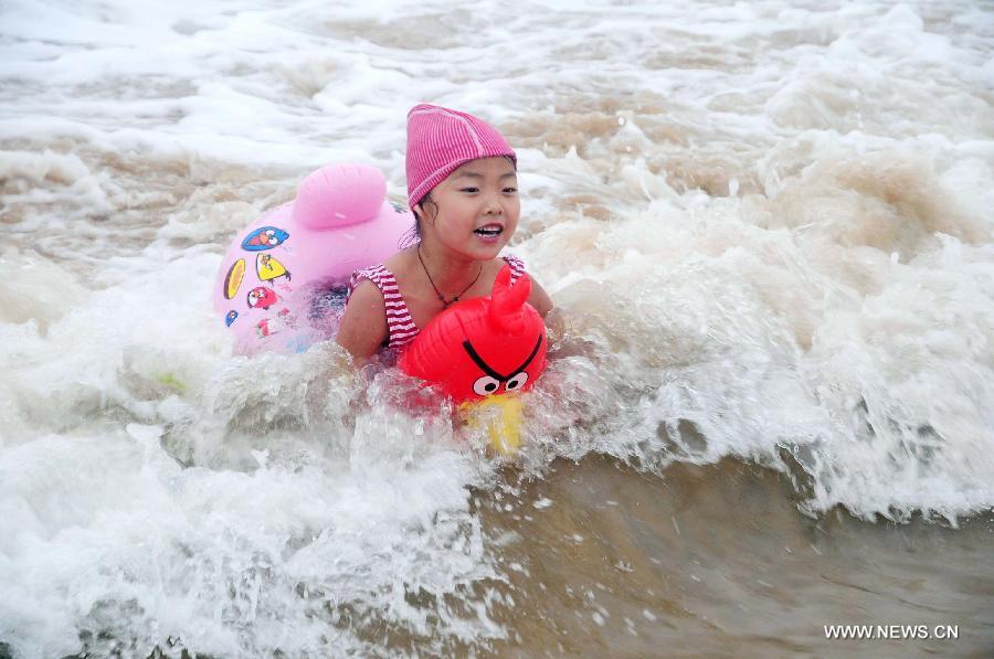 A little girl plays on the Jinshatan bathing beach in Qingdao, east China's Shandong Province, July 13, 2013. Saturday marks the beginning of the hottest part of summer. Many people came to the seashore to spend a cool weekend. (Xinhua/Yu Fangping)