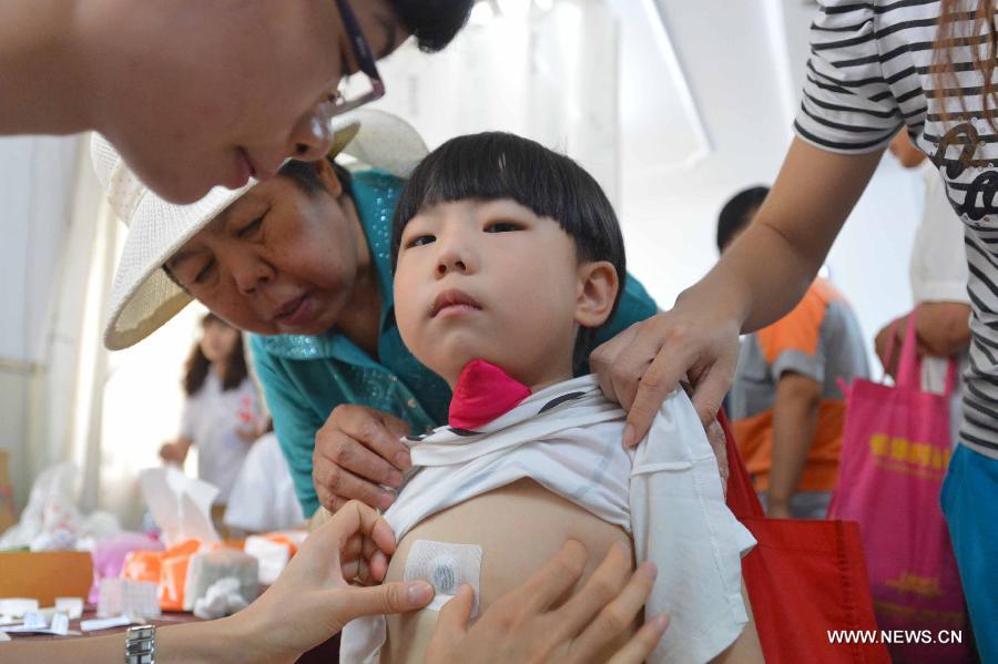 A doctor applies herb sticks to acupuncture points in hot summer days onto a child at a hospital in Tangshan, north China's Hebei Province, July 13, 2013. Saturday marks the beginning of the hottest part of summer. Many people go to their local hospitals of traditional Chinese medicine to apply herb sticks to acupuncture points to prevent diseases. (Xinhua/Zheng Yong)
