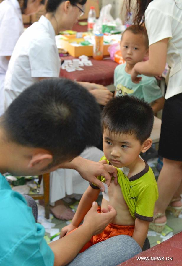 Doctors apply herb sticks to acupuncture points in hot summer days onto children at a hospital in Tangshan, north China's Hebei Province, July 13, 2013. Saturday marks the beginning of the hottest part of summer. Many people go to their local hospitals of traditional Chinese medicine to apply herb sticks to acupuncture points to prevent diseases. (Xinhua/Zheng Yong)