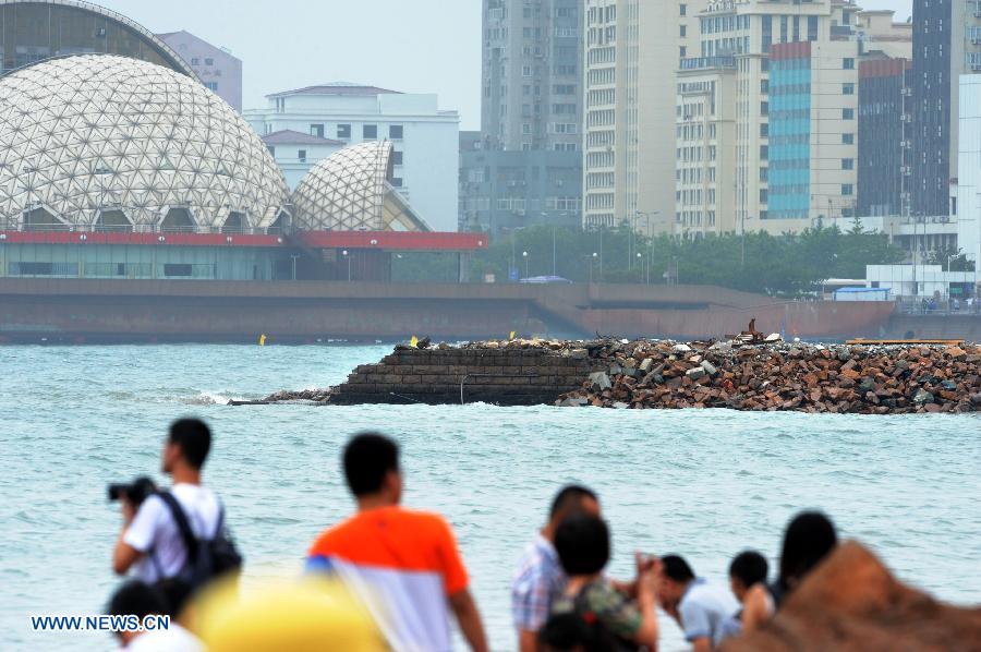Tourists play on the reef near the Zhanqiao Bridge in Qingdao, east China's Shandong Province, July 14, 2013. A renovation work has been started to repair the Zhanqiao Bridge, a landmark for Qingdao. Part of the bridge was hit and destroyed by thunderstorms and waves on May 27. (Xinhua/Li Ziheng) 