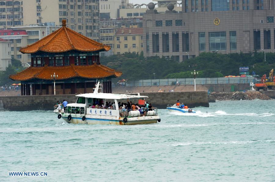 Tourists visit the collapsed Zhanqiao Bridge by boat in Qingdao, east China's Shandong Province, July 14, 2013. A renovation work has been started to repair the Zhanqiao Bridge, a landmark for Qingdao. Part of the bridge was hit and destroyed by thunderstorms and waves on May 27. (Xinhua/Li Ziheng)  