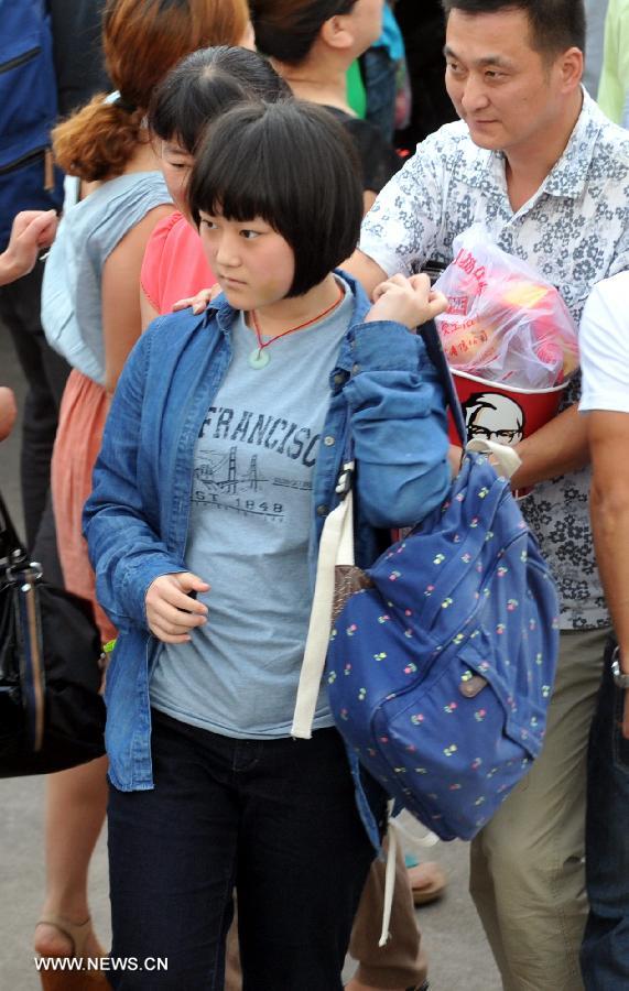 A girl arrives at Jiangshan Middle School in Jiangshan, east China's Zhejiang province, July 14, 2013. A total of 31 students and teachers who were held up in the U.S. by the crashed Asiana Airlines Flight 214 at the San Francisco International Airport returned to Beijing on Saturday and reached home on Sunday. Two Chinese girls were killed on the spot during the crash on July 6. Another girl died on July 12 after succumbing to injuries. (Xinhua/Wang Dingchang)