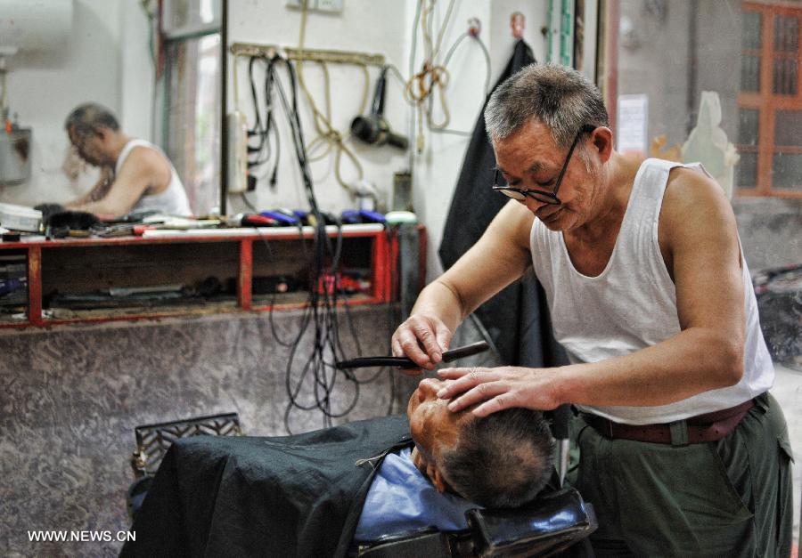 An old barber does a haircut for his customer in the Miao Autonomous County of Chengbu, central China's Hunan Province, July 13, 2013. An ecology tourism festival is held here from July 12 to 14. (Xinhua/Cheng Tingting)