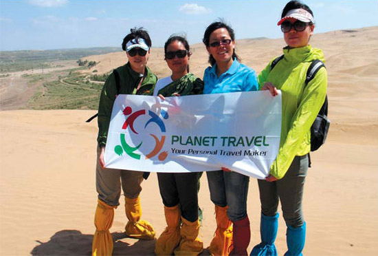 Planet Travel employees Zhou Shuang, Kuang Jiangnan, Liu Fen, a local tour guide and employee He Yong at the Xiangshawan Desert in the city of Erdos, Inner Mongolia. (China Daily)