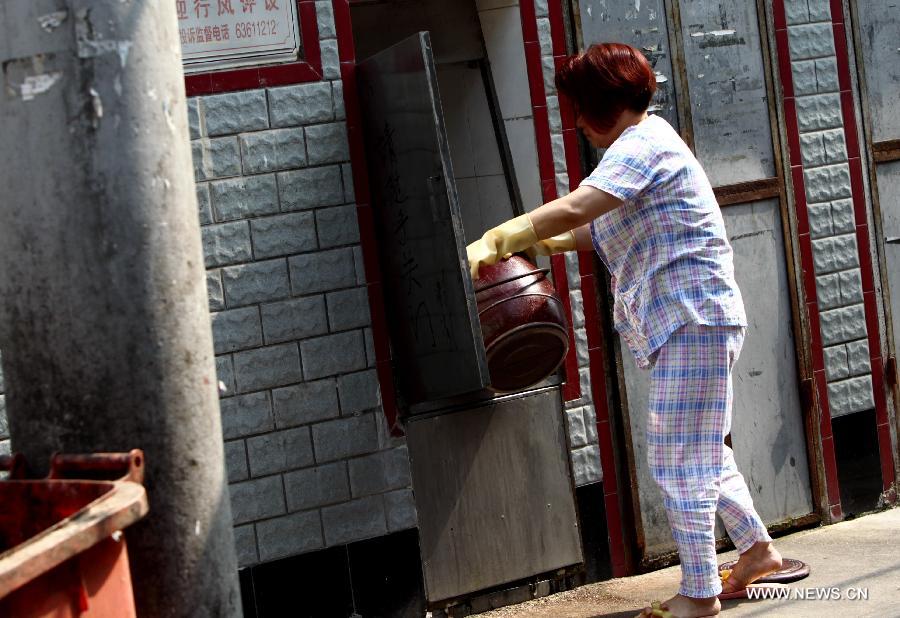 A woman cleans a chamber pot in the Baodai residential area of Yuyuan Street, east China's Shanghai, July 16, 2013. Lacking of independent bathroom, local residents have to use chamber pots as toilets. Shanghai suffers from high temperature in recent days. (Xinhua/Pei Xin) 