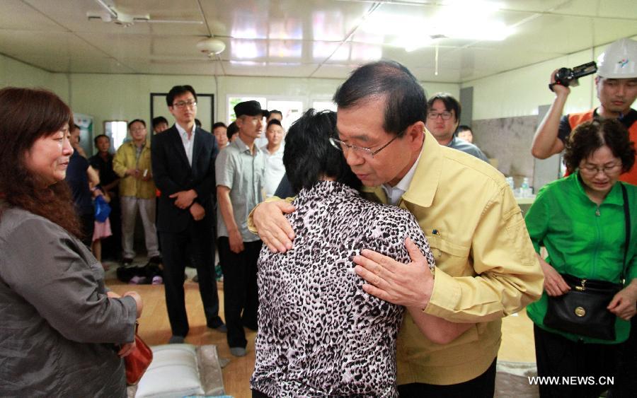Seoul Mayor Park Won-soon (R, front) comforts a relative of the victim in Seoul, capital of South Korea, on July 17, 2013. Rescue workers on Wednesday retrieved the body of one of the six workers who went missing at a flooded underground waterworks construction site in Seoul two days ago, according to Yonhap News Agency. The body was identified as a Chinese worker. (Xinhua)