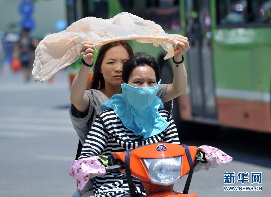 Two women wear sunhats and masks to block the sunshine on a street in Nanning, capital of southwest China's Guangxi Zhuang autonomous region on July 6 2013. The temperature reached 37 degrees Celsius. (Xinhua/Hao Tongqian)