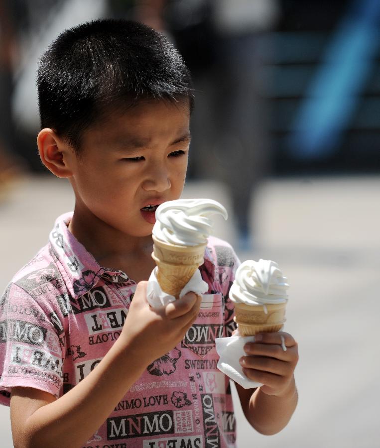 A boy holding ice-cream walks on a pedestrian street in Nanchang, capital of central China's Jiangxi province, July 13, 2013. The temperature of the city reached 36 degrees Celsius. (Xinhua/Zhou Ke)