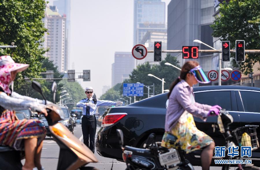 Police officer Rui Caiyun, 24, directs the traffic on a street in Nanjing, capital of east China's Jiangsu province on July 12, 2013. Her daily working time is from 7:15 a.m. to 11:30 a.m. and 3 p.m. to 6 p.m. The weather station of Jiangsu province issued a yellow warning of high temperature from July 8 to 10. The temperature of most parts of Jiangsu reached 35 degrees Celsius. (Photo/Xinhua)