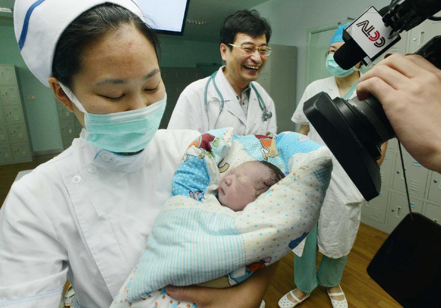 A nurse hugs the baby girl of Qiu, the first pregnant woman in the world infected with H7N9 bird flu, in the No.1 People's Hospital of Zhenjiang, east China's Jiangsu Province, July 17, 2013. Diagnosed as H7N9 bird flu patient on April 8, 2013, Qiu gave birth to a girl here on Wednesday. (Xinhua/Wang Cheng) 
