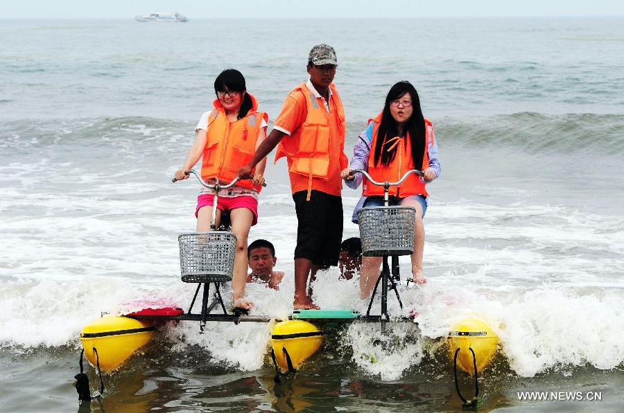 Tourists ride water bike at the Wanpingkou bathing beach in Rizhao, east China's Shandong Province, July 19, 2013. A large amount of tourists come here to enjoy the coolness brought by sea. (Xinhua/Yu Fangping) 