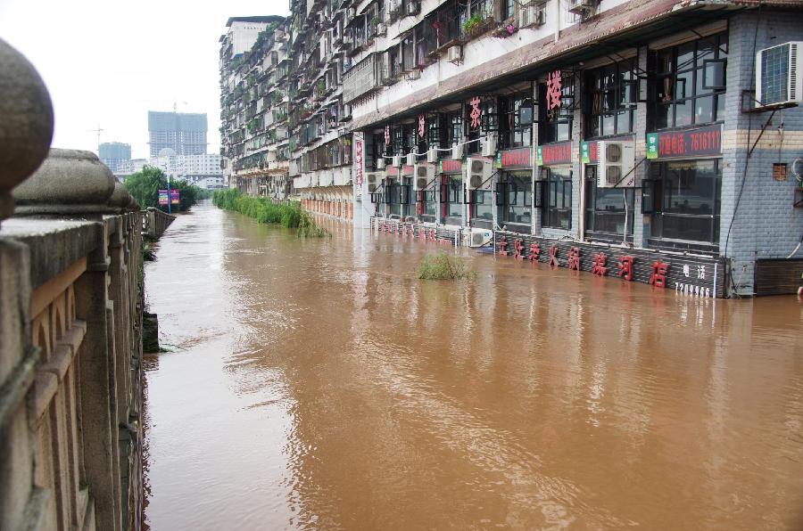 Shops at the first floor of a building are submerged in water on Binhe Road in Quxian County of Dazhou City, southwest China's Sichuan Province, July 20, 2013. Due to sustained heavy rainfall, this year's highest flood peak of the Qujiang River which runs through northeast Sichuan and west Chongqing, a southwest China's municipality near Sichuan, passed Quxian County Saturday. More than one third of the downtown area of Quxian County was flooded. (Xinhua/Yu Junhua)