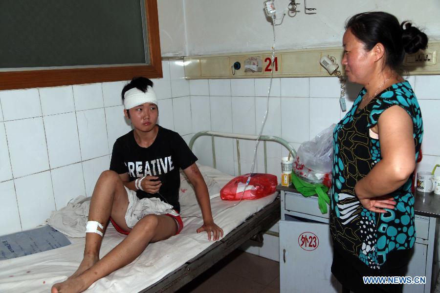 A victim of the landslide in the Jinsixia Gorge receives treatment in a hospital in Shangnan County, northwest China's Shaanxi Province, July 21, 2013. One tourist was killed and 18 others injured by falling rocks at Jinsixia Gorge on Sunday morning. The gorge has been closed temporarily. (Xinhua)